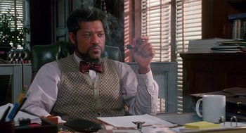 Movie still from “Higher Learning” (1995), directed by John Singleton – A man sitting at a table with a cigarette in his hand; Medium shot, Low angle
