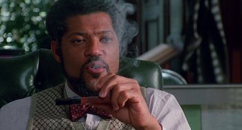 Movie still from “Higher Learning” (1995), directed by John Singleton – A man sitting in a chair smoking a pipe; Close Up shot, Low angle