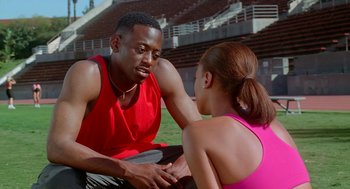 Movie still from “Higher Learning” (1995), directed by John Singleton – A man and a woman sitting on the ground talking to each other; Medium shot, Over the shoulder angle