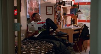 Movie still from “Higher Learning” (1995), directed by John Singleton – A man sitting on a bed reading a magazine; Wide shot, High angle