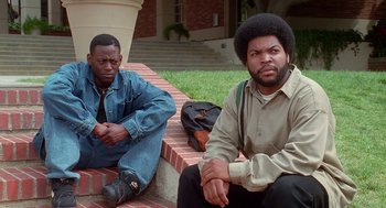 Movie still from “Higher Learning” (1995), directed by John Singleton – Two men sitting on steps in front of a building; Medium shot, Low angle