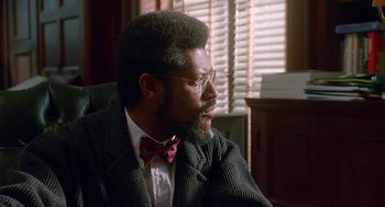 Movie still from “Higher Learning” (1995), directed by John Singleton – A man sitting in a chair wearing a bow tie; Close Up shot, Over the shoulder angle