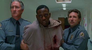 Movie still from “Higher Learning” (1995), directed by John Singleton – A police officer and two other men holding a man in a hooded sweatshirt; Medium shot, Over the shoulder angle
