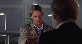 Movie still from “Highlander” (1986), directed by Russell Mulcahy – A man holding a sword in front of another man in a suit; Close Up shot, Over the shoulder angle