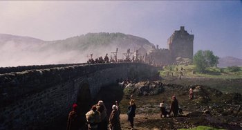 Movie still from “Highlander” (1986), directed by Russell Mulcahy – A group of people standing on top of a stone bridge; Extreme Wide shot, Low angle