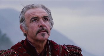 Movie still from “Highlander” (1986), directed by Russell Mulcahy – An older man with grey hair wearing a red shirt; Close Up shot, Low angle