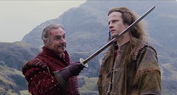 Movie still from “Highlander” (1986), directed by Russell Mulcahy – Two men in medieval garb holding a sword; Medium shot, Over the shoulder angle