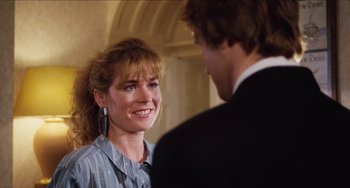 Movie still from “Highlander” (1986), directed by Russell Mulcahy – A woman smiles at a man in a suit; Close Up shot, Over the shoulder angle