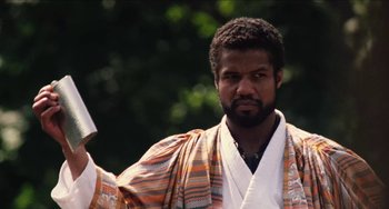 Movie still from “Highlander” (1986), directed by Russell Mulcahy – A man in a robe is holding a book; Close Up shot, Low angle