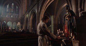 Movie still from “Highlander” (1986), directed by Russell Mulcahy – A man standing in front of candles in a church; Wide shot, Low angle
