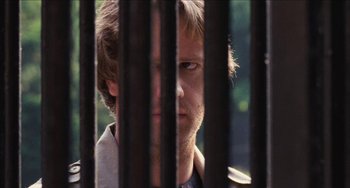 Movie still from “Highlander” (1986), directed by Russell Mulcahy – A person behind a metal fence; Close Up shot, Over the shoulder angle