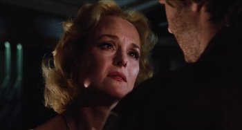 Movie still from “Highlander” (1986), directed by Russell Mulcahy – An older woman looking down at a man in a dark room; Close Up shot, Over the shoulder angle