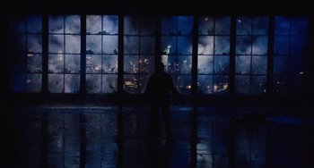Movie still from “Highlander” (1986), directed by Russell Mulcahy – A person in a dark room holding a sword; Extreme Wide shot, Low angle