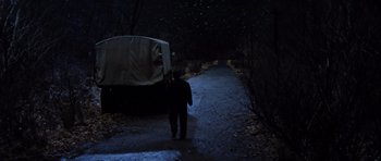 Movie still from “Hoffa” (1992), directed by Danny DeVito – A man walking down a dark path next to a truck at night; Wide shot, High angle
