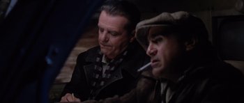 Movie still from “Hoffa” (1992), directed by Danny DeVito – Two men sitting next to each other while smoking a cigarette; Close Up shot, Over the shoulder angle