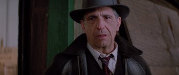 Movie still from “Hoffa” (1992), directed by Danny DeVito – An older man wearing a hat and a tie; Close Up shot, Over the shoulder angle