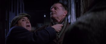 Movie still from “Hoffa” (1992), directed by Danny DeVito – A man is holding a pair of scissors up to his neck; Close Up shot, Over the shoulder angle