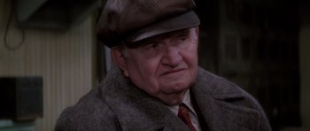 Movie still from “Hoffa” (1992), directed by Danny DeVito – An older man wearing a hat and a jacket; Close Up shot, Over the shoulder angle