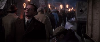 Movie still from “Hoffa” (1992), directed by Danny DeVito – A group of people walking down a street holding torches; Medium shot, High angle
