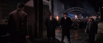 Movie still from “Hoffa” (1992), directed by Danny DeVito – A couple of men standing next to each other on a street; Wide shot, Low angle