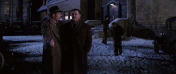 Movie still from “Hoffa” (1992), directed by Danny DeVito – A couple of men standing next to each other on a snowy day; Medium shot, Over the shoulder angle