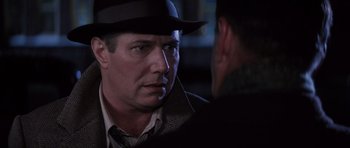 Movie still from “Hoffa” (1992), directed by Danny DeVito – A man wearing a hat and a tie talking to another man wearing a suit; Close Up shot, Over the shoulder angle