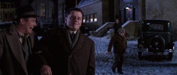 Movie still from “Hoffa” (1992), directed by Danny DeVito – A man in a brown coat and a man in a black suit and a man in a brown hat and a man in a brown coat and a; Medium shot, Low angle