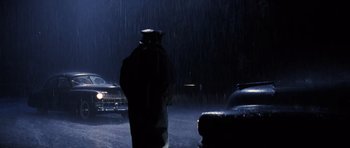 Movie still from “Hoffa” (1992), directed by Danny DeVito – A man in a raincoat standing in the middle of the street; Wide shot, Over the shoulder angle