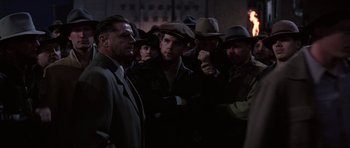 Movie still from “Hoffa” (1992), directed by Danny DeVito – A group of men standing next to each other in a dark room; Medium shot, Over the shoulder angle