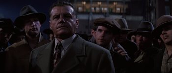 Movie still from “Hoffa” (1992), directed by Danny DeVito – A man in a suit and hat standing next to another man in a hat; Close Up shot, Low angle