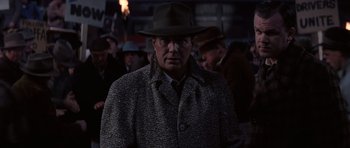 Movie still from “Hoffa” (1992), directed by Danny DeVito – A man wearing a hat and a coat in the dark; Close Up shot, Over the shoulder angle