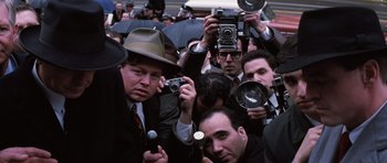 Movie still from “Hoffa” (1992), directed by Danny DeVito – A group of people holding cameras and taking pictures; Medium shot, High angle