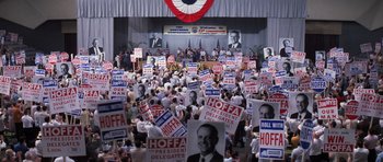 Movie still from “Hoffa” (1992), directed by Danny DeVito – A crowd of people holding political signs at a political event; Extreme Wide shot, High angle