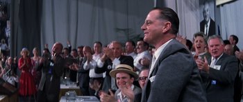 Movie still from “Hoffa” (1992), directed by Danny DeVito – A group of people sitting in a room clapping; Medium shot, Over the shoulder angle