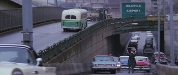 Movie still from “Hoffa” (1992), directed by Danny DeVito – A bus driving down a street next to a bridge; Extreme Wide shot, High angle