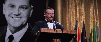 Movie still from “Hoffa” (1992), directed by Danny DeVito – A man standing at a podium with a microphone; Medium shot, Low angle