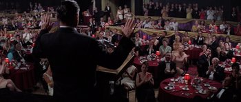 Movie still from “Hoffa” (1992), directed by Danny DeVito – A crowd of people sitting at tables in front of a microphone; Wide shot, Over the shoulder angle