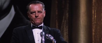 Movie still from “Hoffa” (1992), directed by Danny DeVito – A man in a tuxedo standing in front of microphones; Close Up shot, Low angle