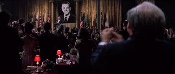 Movie still from “Hoffa” (1992), directed by Danny DeVito – A crowd of people sitting at tables in front of a microphone; Extreme Wide shot, Low angle