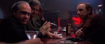 Movie still from “Hoffa” (1992), directed by Danny DeVito – A group of people sitting at a table with drinks; Medium shot, Over the shoulder angle
