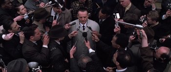 Movie still from “Hoffa” (1992), directed by Danny DeVito – A group of men holding microphones in front of a man in a suit; Medium shot, High angle