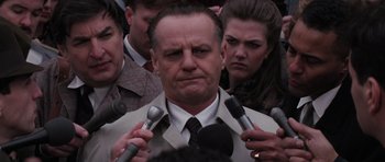 Movie still from “Hoffa” (1992), directed by Danny DeVito – A group of people holding microphones in front of a man in a suit; Close Up shot, Over the shoulder angle