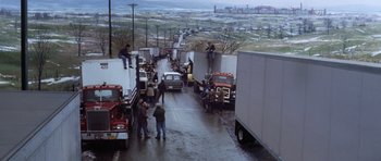 Movie still from “Hoffa” (1992), directed by Danny DeVito – A group of men standing next to a large truck; Extreme Wide shot, High angle
