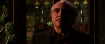Movie still from “Hoffa” (1992), directed by Danny DeVito – An older man in a black jacket and a red shirt; Close Up shot, Low angle
