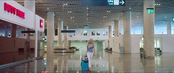 Movie still from “Holiday” (2018), directed by Isabella Eklöf – A woman walking through an airport with her luggage; Wide shot, Low angle