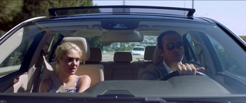 Movie still from “Holiday” (2018), directed by Isabella Eklöf – A man and a woman sitting in the back seat of a car; Medium shot, Over the shoulder angle