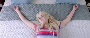 Movie still from “Holiday” (2018), directed by Isabella Eklöf – A woman laying on top of a bed with her arms up; Medium shot, Overhead angle