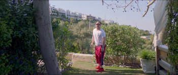 Movie still from “Holiday” (2018), directed by Isabella Eklöf – A man standing in a park holding a frisbee; Wide shot, Low angle