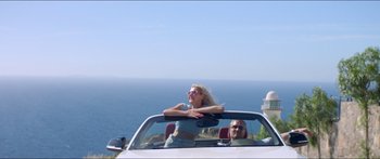Movie still from “Holiday” (2018), directed by Isabella Eklöf – A woman sitting in the back seat of a convertible car; Wide shot, Low angle