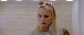 Movie still from “Holiday” (2018), directed by Isabella Eklöf – A woman with blonde hair wearing pink sunglasses; Close Up shot, Over the shoulder angle
